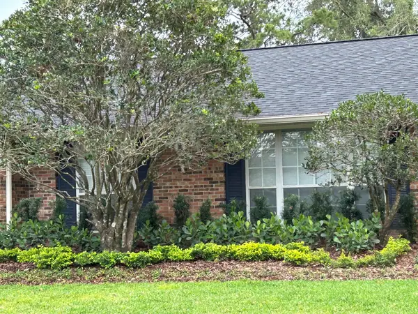 Brick ranch house with new shrub beds under a crape myrtle and mulch edging the lawn