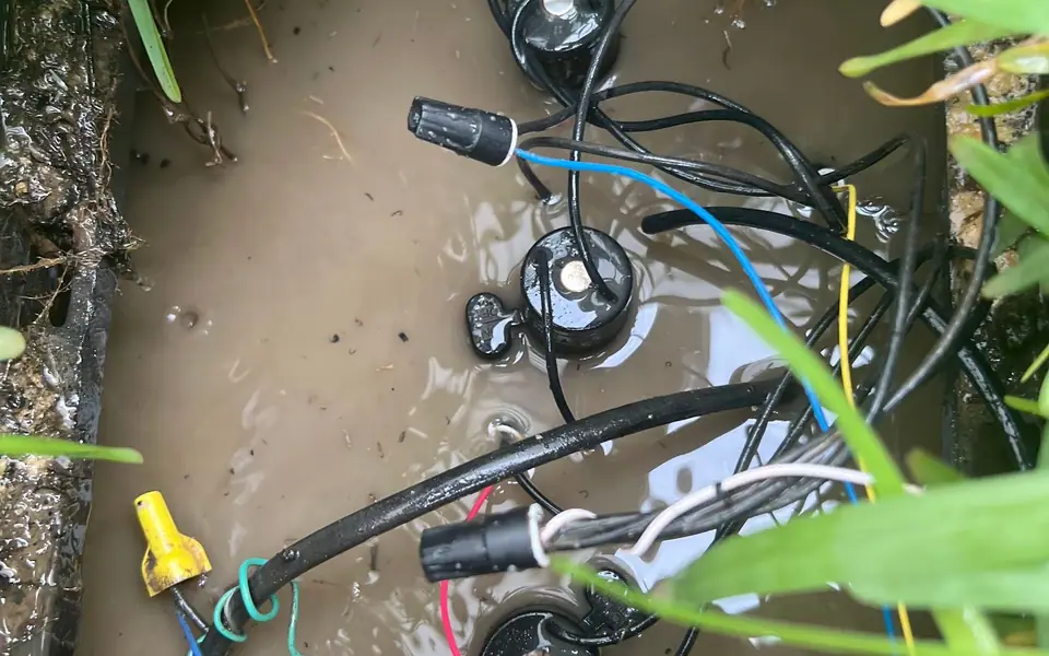 Irrigation valve manifold in an open valve box with solenoid wiring, mid-repair