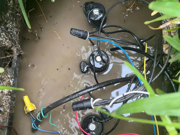 Sprinkler valves and solenoid wiring in an open valve box during a repair