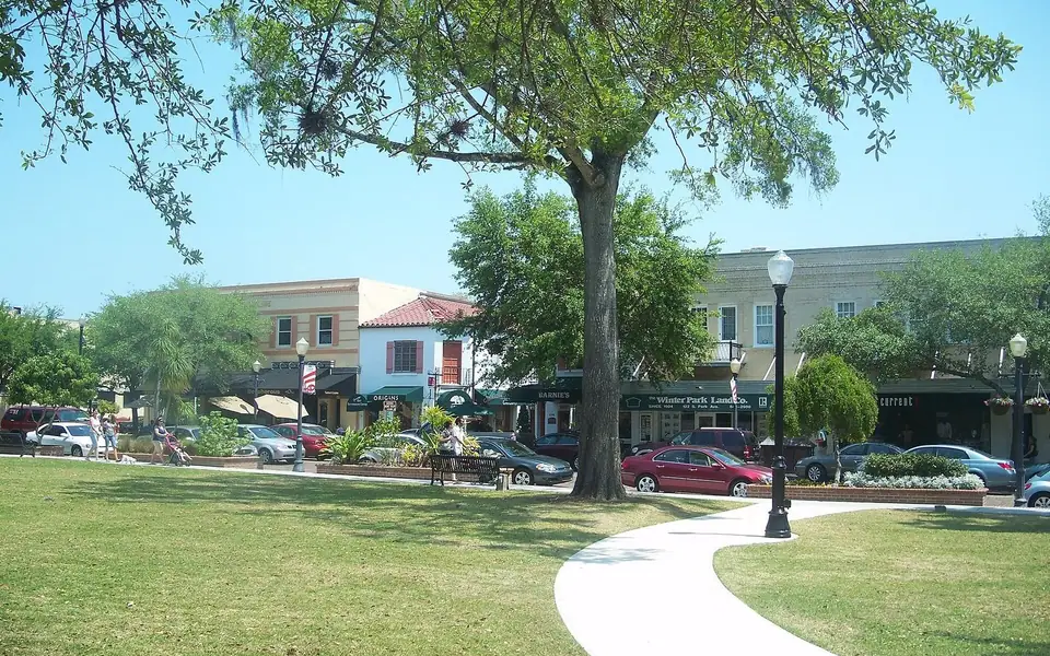 Central Park lawn under live oaks with the Park Avenue storefronts behind, Downtown Winter Park Historic District