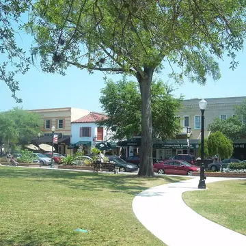 Central Park lawn under live oaks with the Park Avenue storefronts behind, Downtown Winter Park Historic District
